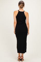 woman wearing a black ribbed maternity dress with a fitted silhouette and a mid-calf length from the back