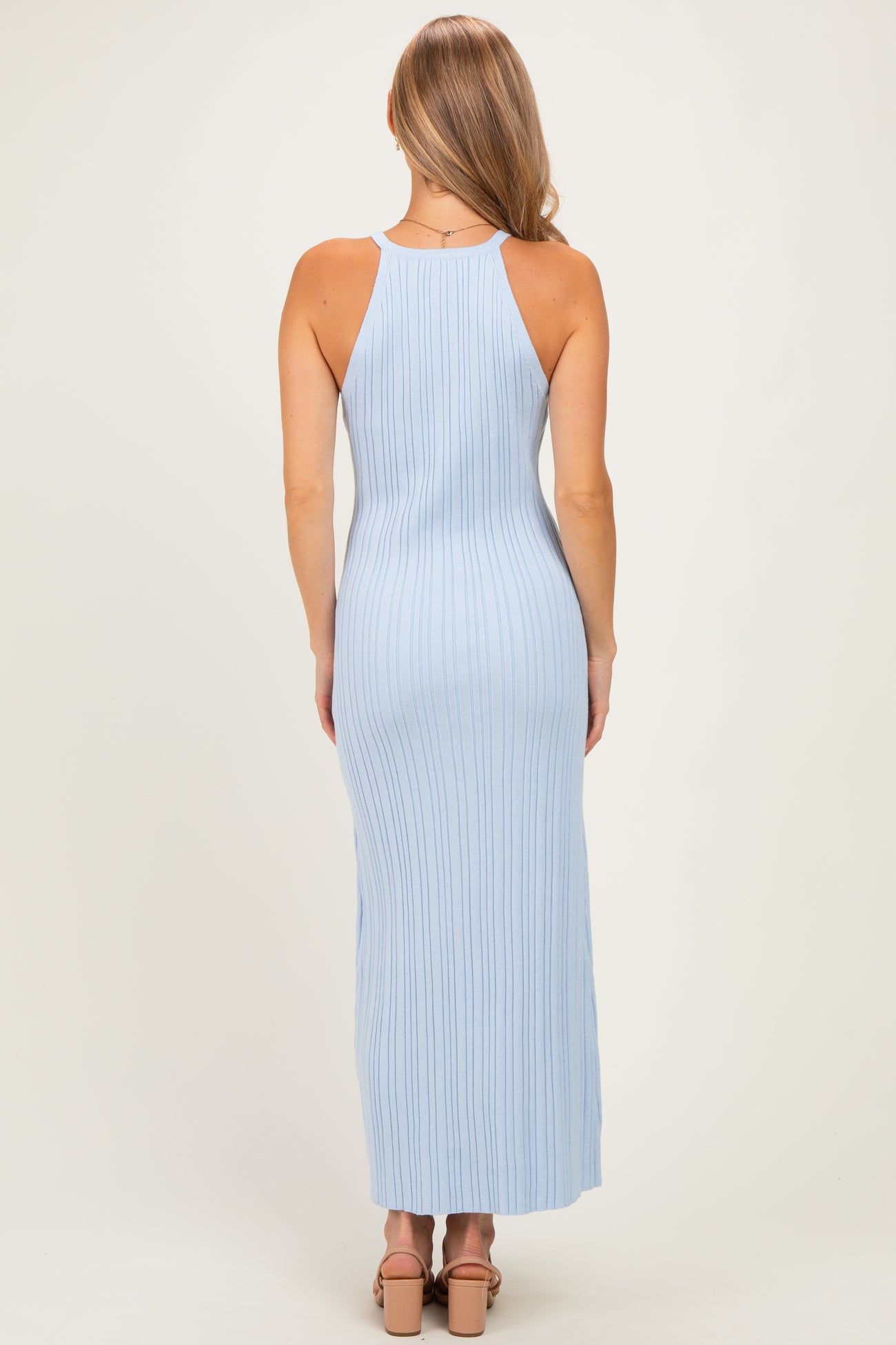 woman wearing a light blue ribbed maxi dress with a racerback style and fitted silhouette, seen from the back