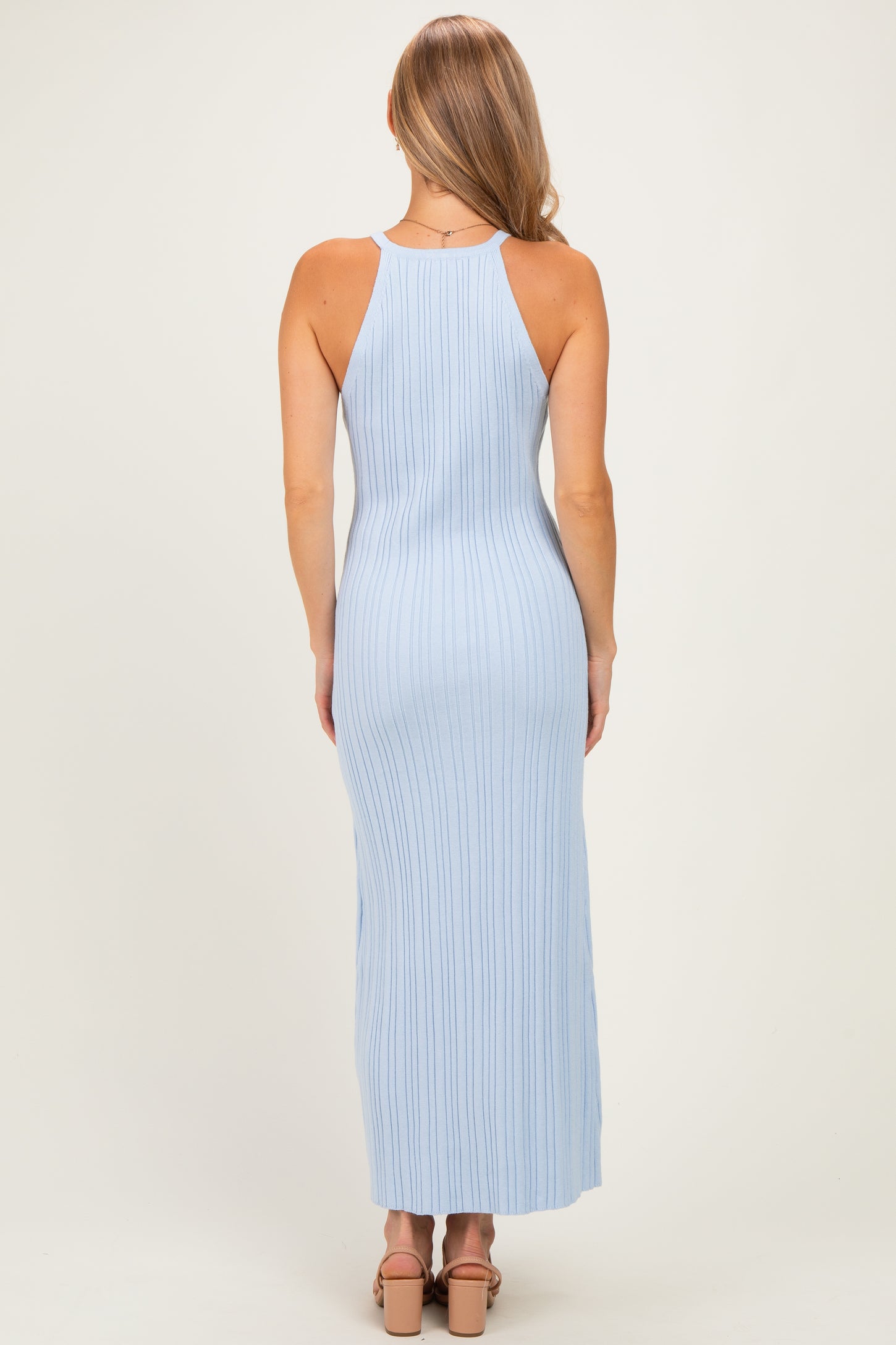 woman wearing a light blue ribbed maxi dress with a racerback style and fitted silhouette, seen from the back