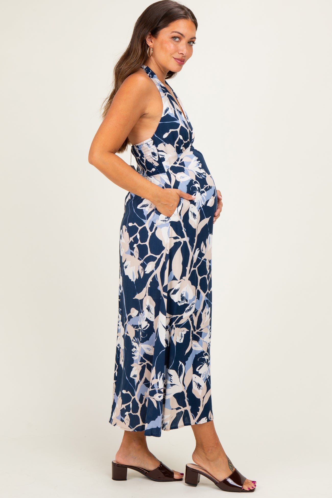 woman wearing a navy floral maternity maxi dress with pockets and a visible baby bump