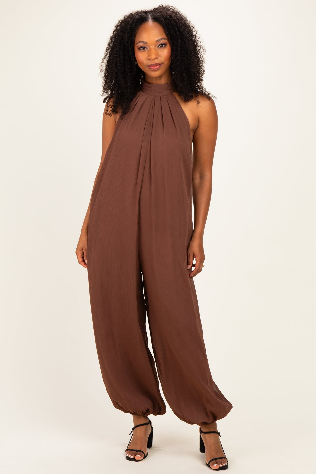 woman wearing a brown halter-neck jumpsuit with wide legs and a flowy silhouette