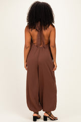 woman wearing a brown halter-back jumpsuit with wide legs and open back, shown from the back