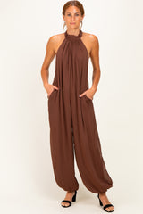 woman wearing a brown halter neck jumpsuit with side pockets and tapered legs