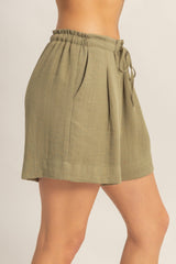 woman wearing olive green high-waisted shorts with a drawstring waist and side pleats