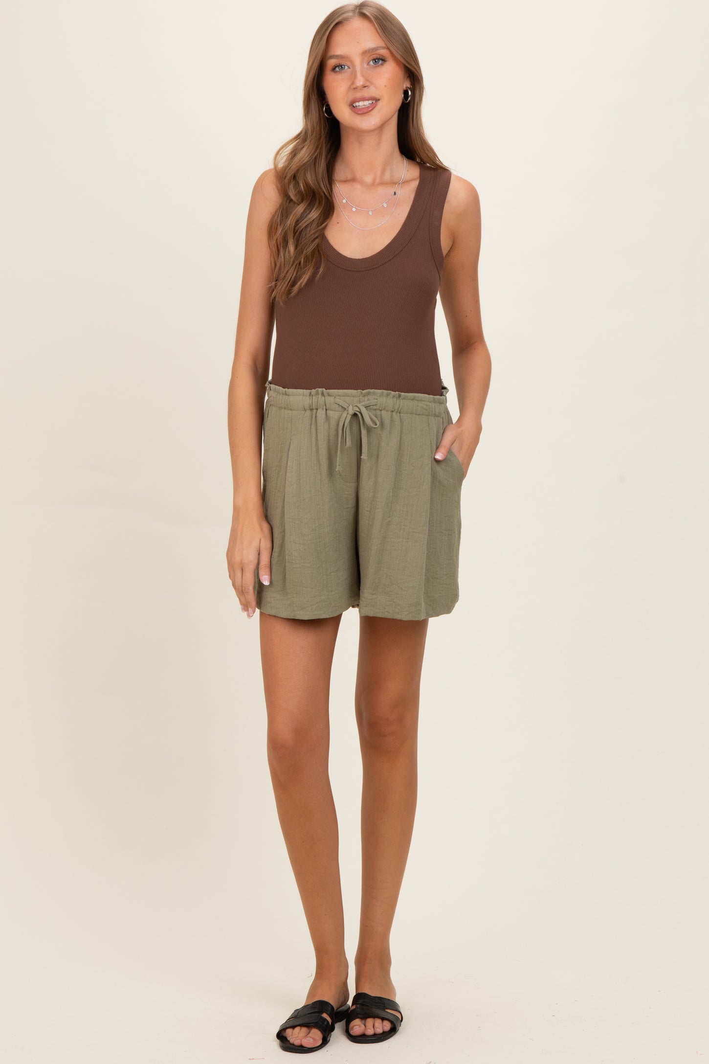 woman wearing a brown ribbed tank top and green maternity shorts with pockets