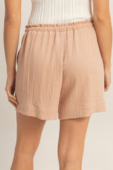 woman wearing light pink elastic waist shorts with a relaxed fit and textured fabric, view from the back