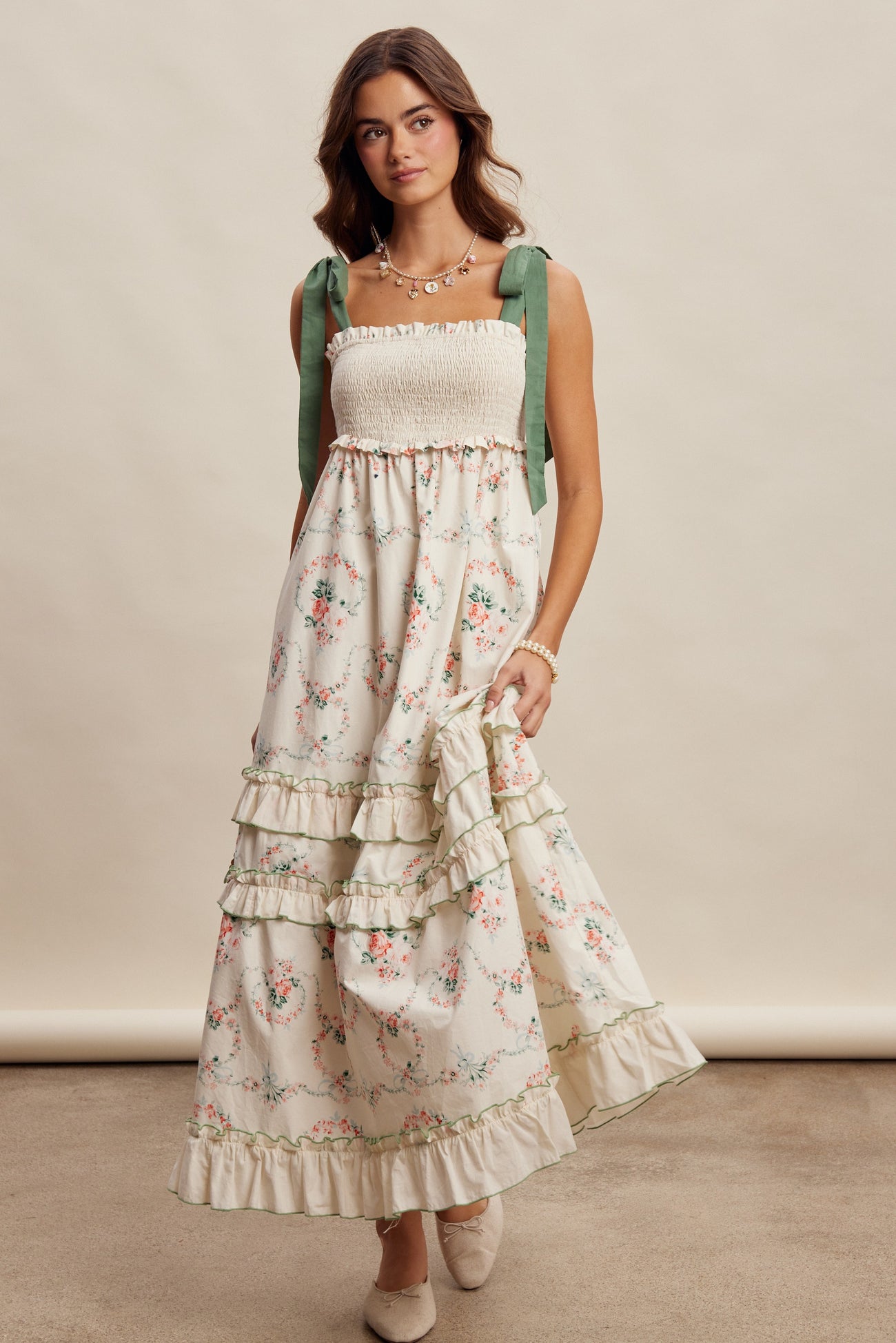woman wearing a floral maxi dress with smocked bodice, ruffled tiers, and green bow straps