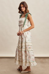 woman wearing a floral maxi dress with a smocked bodice and green ribbon straps, standing sideways against a neutral background