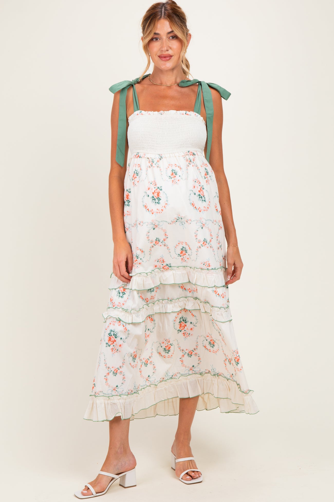 woman wearing a floral maternity maxi dress with ruffle tiers and tie straps, showcasing her baby bump