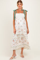 woman wearing a floral maternity maxi dress with ruffle tiers and tie straps, showcasing her baby bump