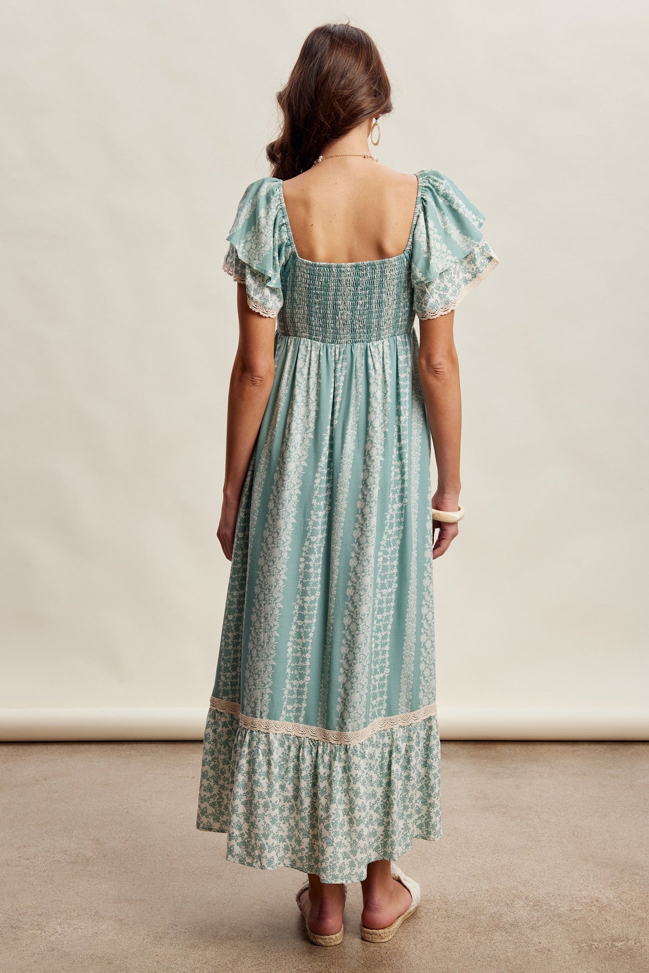 woman wearing a mint green maxi dress with short puff sleeves and a smocked back, featuring floral prints