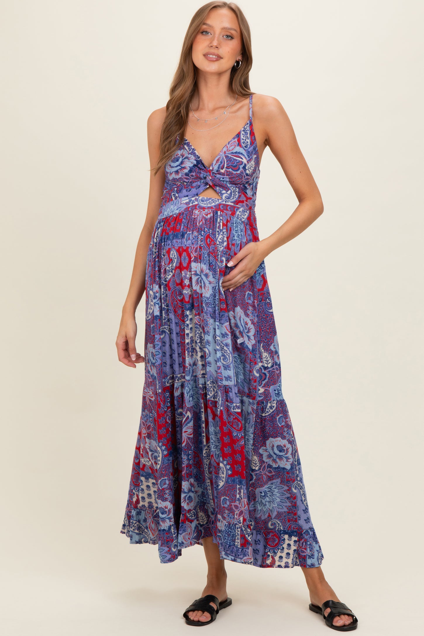 woman wearing a blue and red printed maternity maxi dress, holding her baby bump