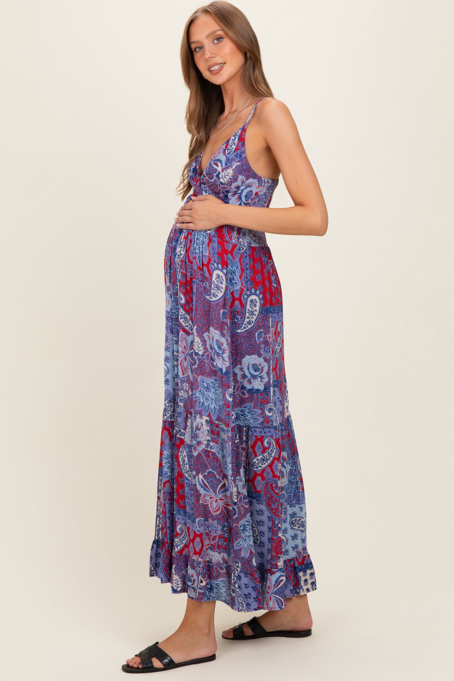 woman wearing a patterned purple maxi maternity dress and holding her baby bump