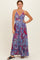 woman wearing a red and blue patterned maxi dress with a tied front detail and thin straps
