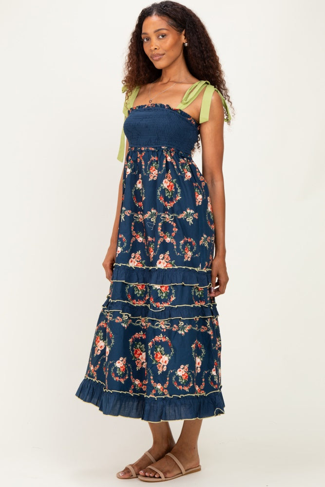 woman wearing a navy floral maxi dress with smocked bodice and green tie straps