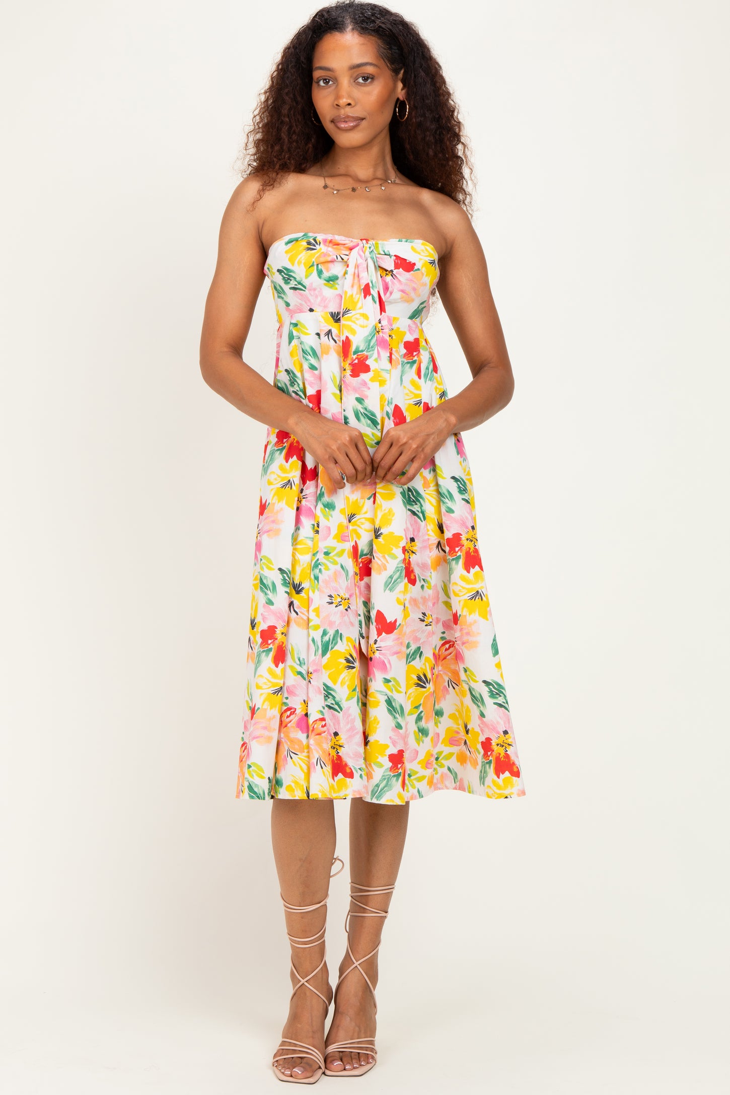 woman wearing a floral strapless midi dress with a tie front detail and a flared skirt