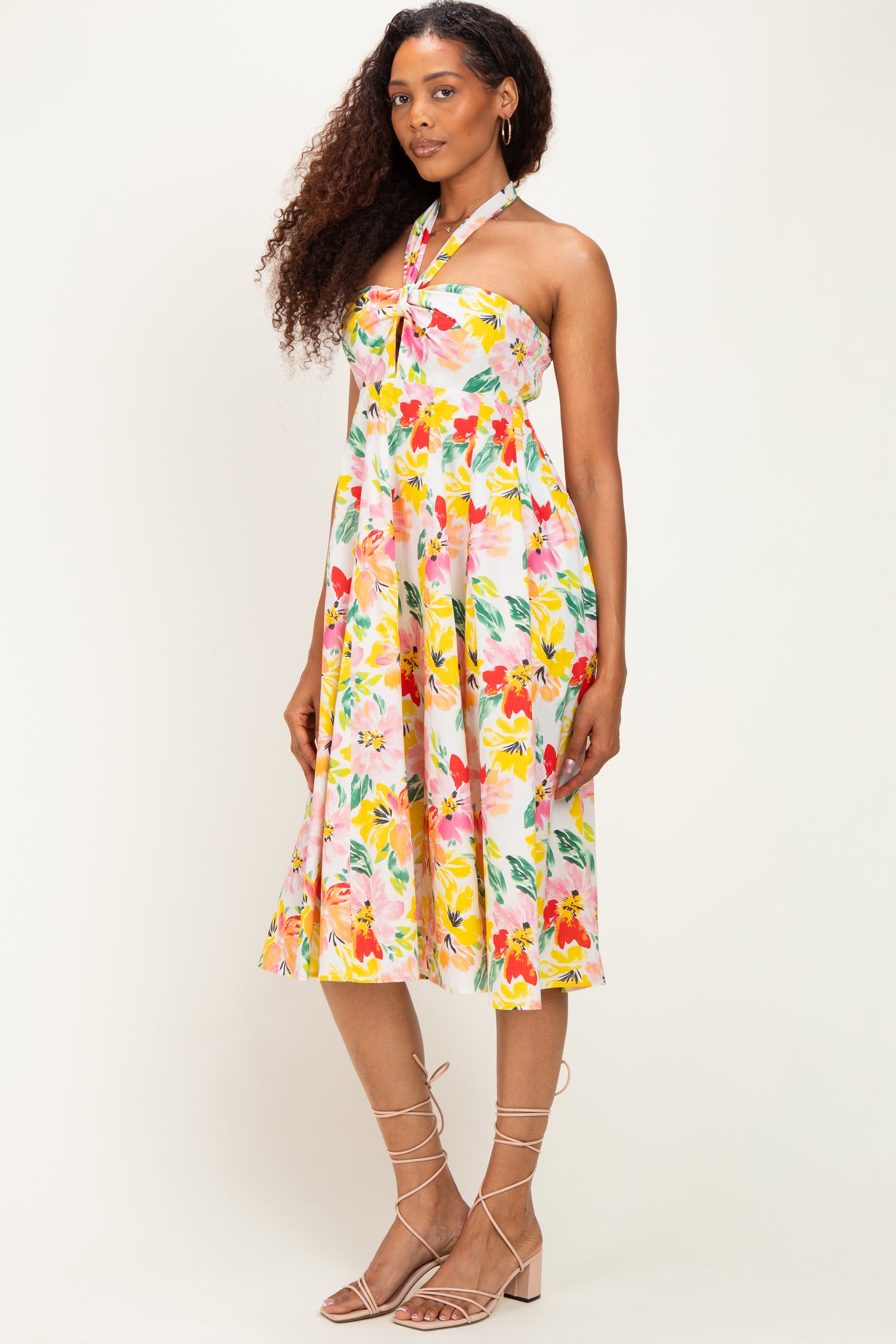woman wearing a floral halter neck dress with a fitted bodice and flowing skirt, standing against a neutral background