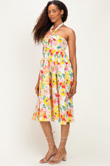 woman wearing a floral halter neck dress with a fitted bodice and flowing skirt, standing against a neutral background