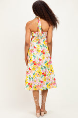 woman wearing a floral print halter neck midi dress with a fitted bodice and flowy skirt