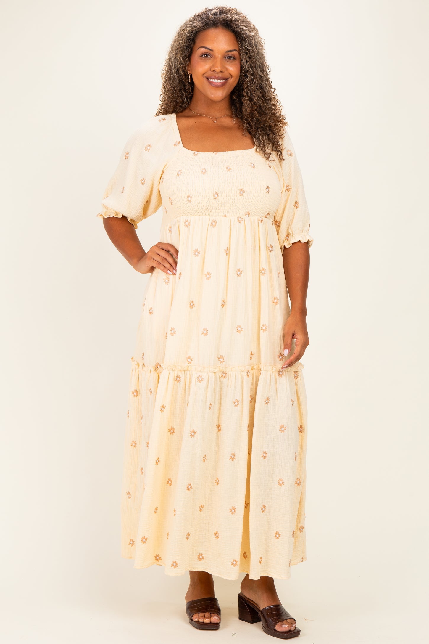 woman wearing a yellow floral plus-size maxi dress with short puff sleeves and a tiered skirt