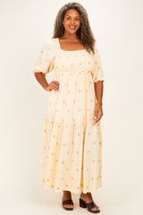 woman wearing a yellow floral plus-size maxi dress with short puff sleeves and a tiered skirt