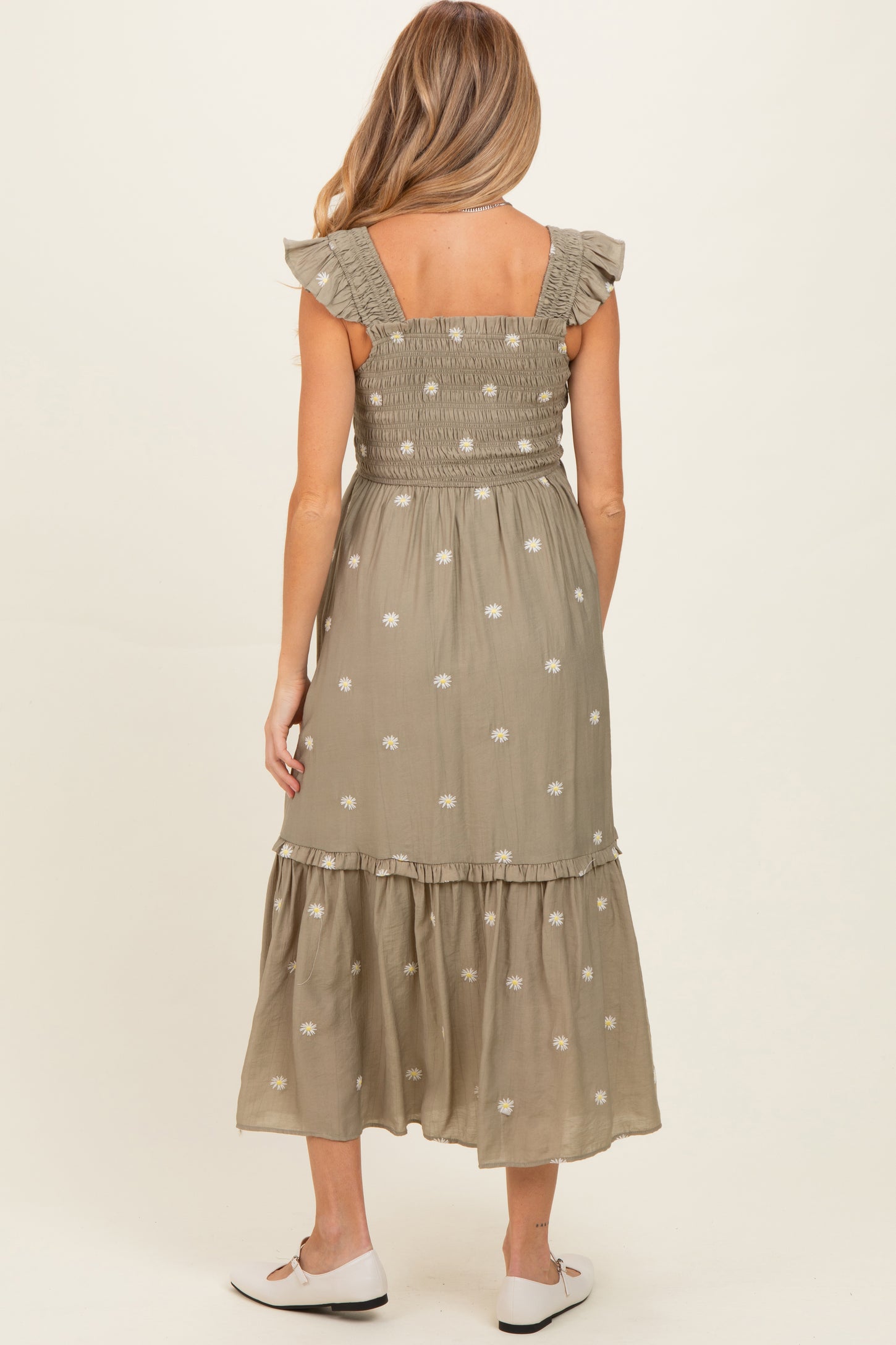 woman wearing a green floral embroidered maternity maxi dress with ruffled straps and a smocked back