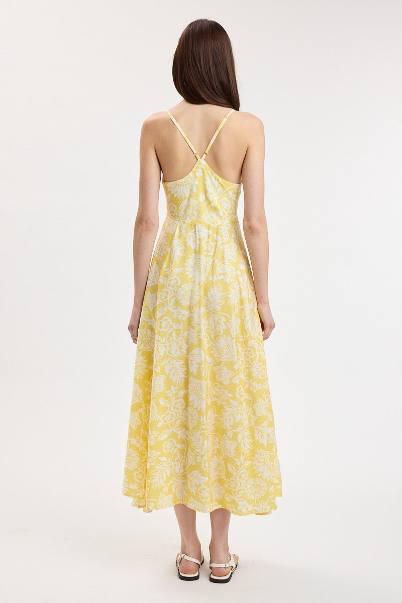 woman wearing a yellow floral midi dress with spaghetti straps, showing the back view