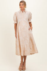 woman wearing a beige maternity dress with paisley print, short puff sleeves, and button front detail, showcasing her baby bump