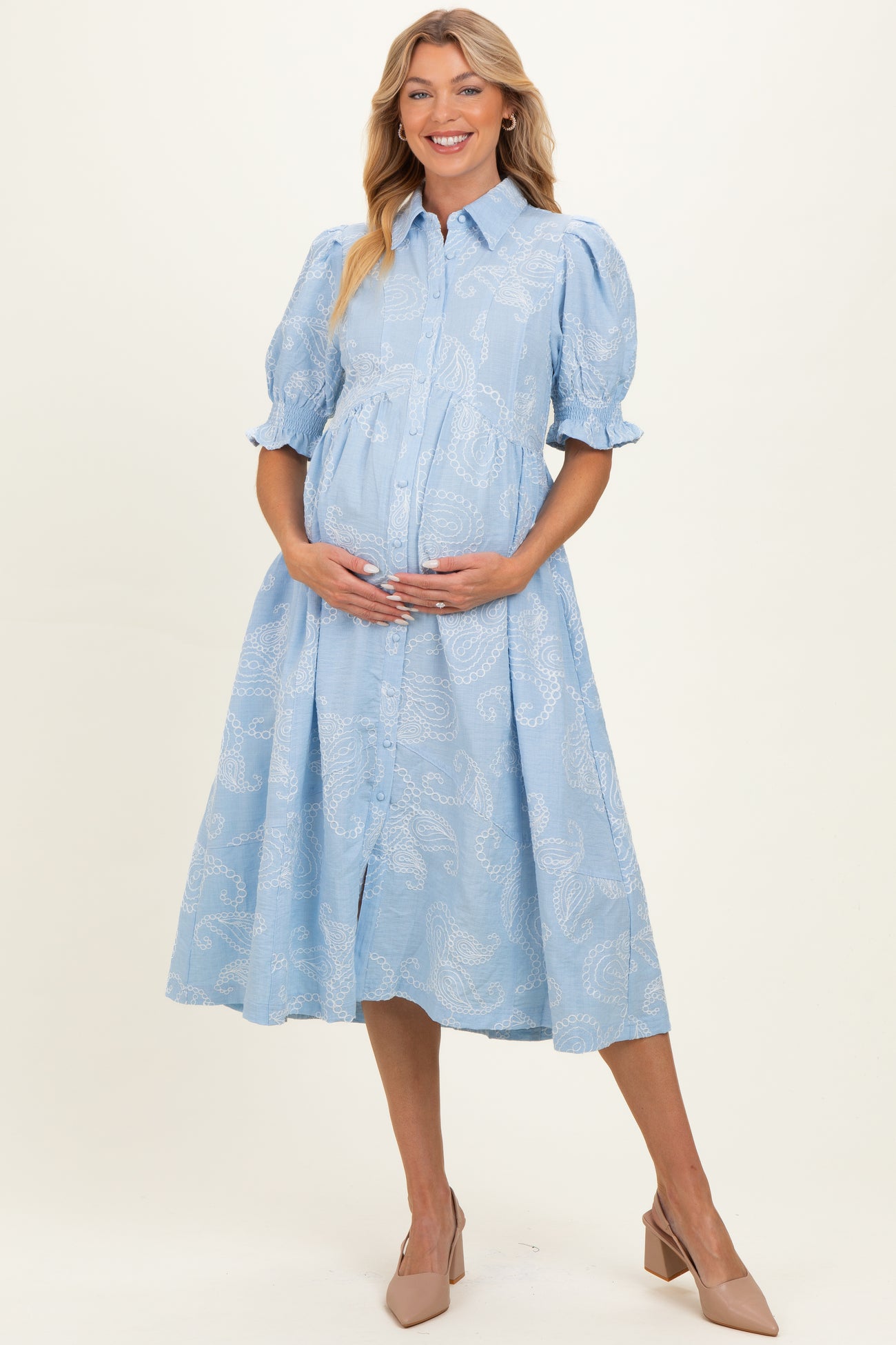 woman wearing a light blue button-up maternity dress with puff sleeves and a visible baby bump
