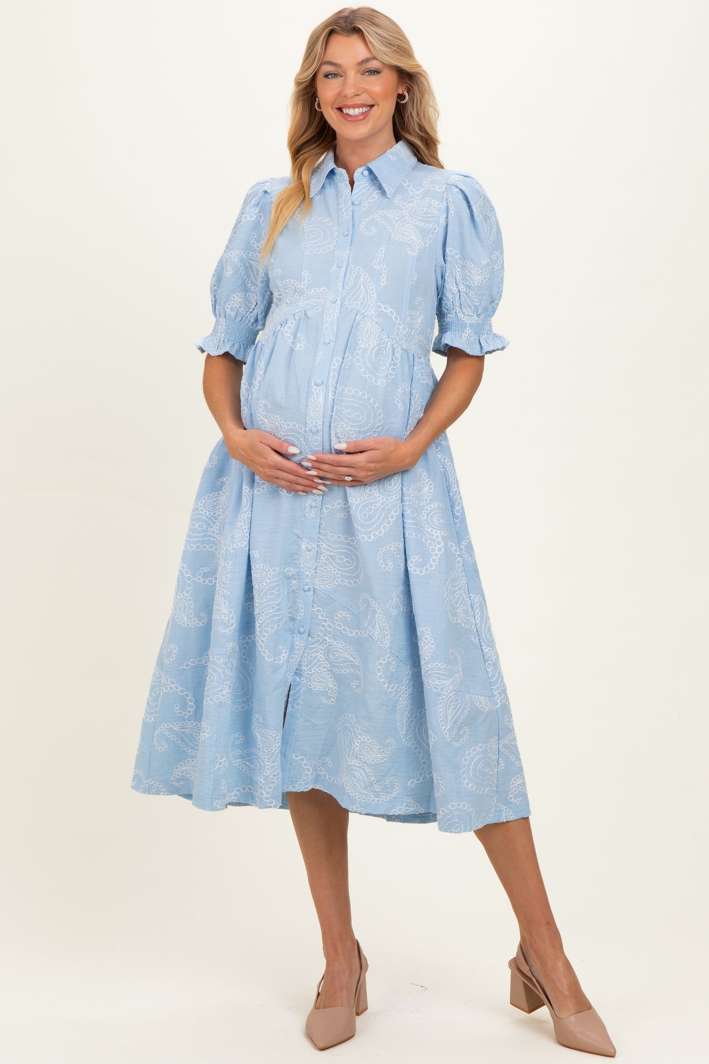 woman wearing a light blue button-up maternity dress with puff sleeves and a visible baby bump