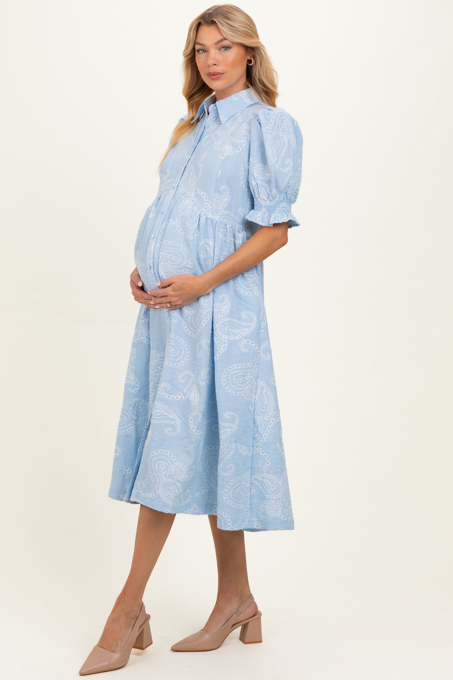 woman wearing a light blue paisley print maternity dress with puff sleeves and a visible baby bump