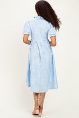 woman wearing a light blue paisley print midi dress with puff sleeves and a belted waist, viewed from the back