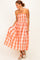 woman wearing an orange and white plaid strapless maxi dress with a smocked bodice and flowing skirt