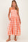 woman wearing a pink and orange checkered strapless maternity dress with a smocked bodice and a flowy skirt