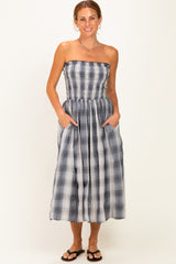 woman wearing a strapless midi dress with a gray and white plaid pattern and side pockets