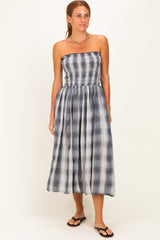 woman wearing a strapless plaid midi dress in navy and white with a gathered waist and a flowing skirt