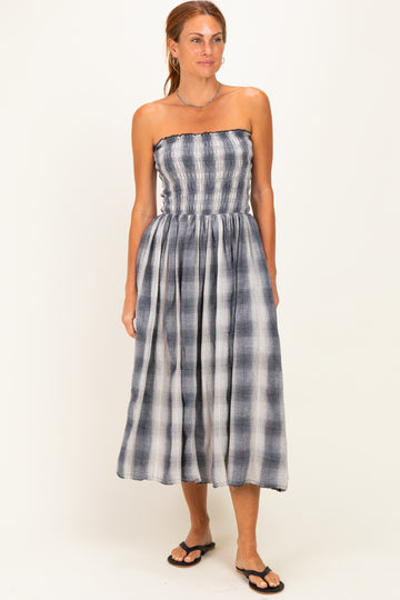 woman wearing a strapless plaid midi dress in navy and white with a gathered waist and a flowing skirt