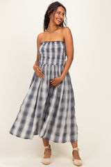 woman wearing a navy and white striped maternity maxi dress with a smocked bodice and holding her baby bump