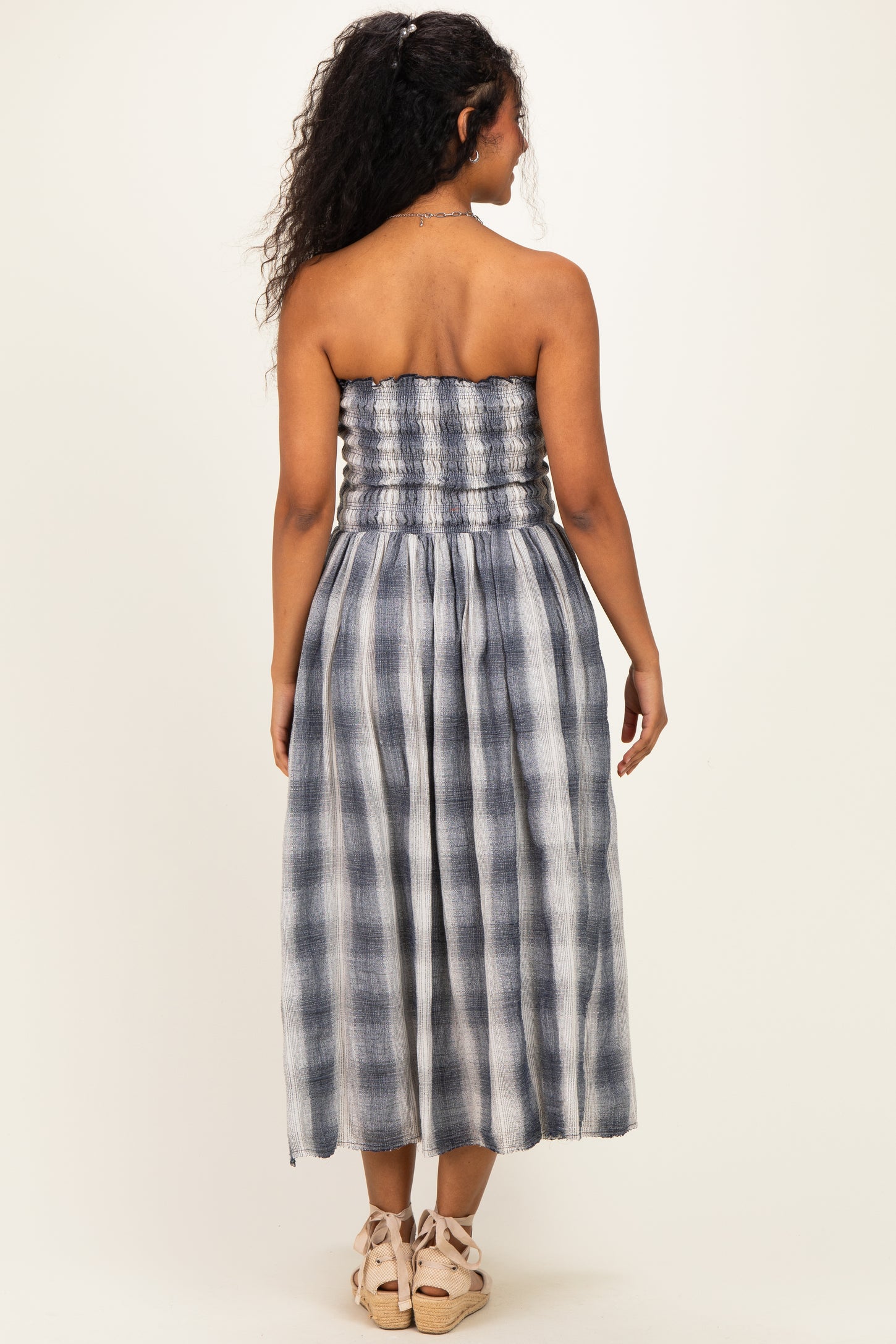 woman wearing a navy and white checkered strapless maternity dress with a smocked bodice and flowing skirt