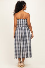 woman wearing a navy and white checkered strapless maternity dress with a smocked bodice and flowing skirt