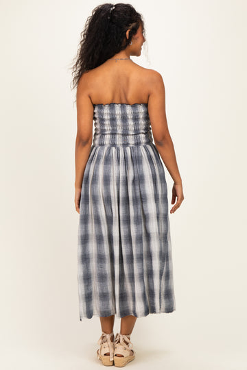 woman wearing a navy and white checkered strapless maternity dress with a smocked bodice and flowing skirt