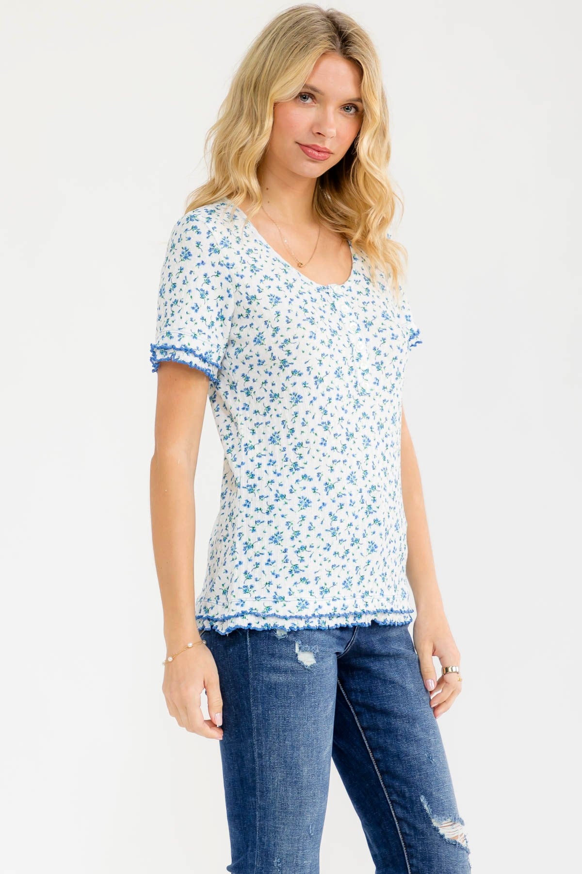 woman wearing a floral print short sleeve top with blue trim and distressed jeans