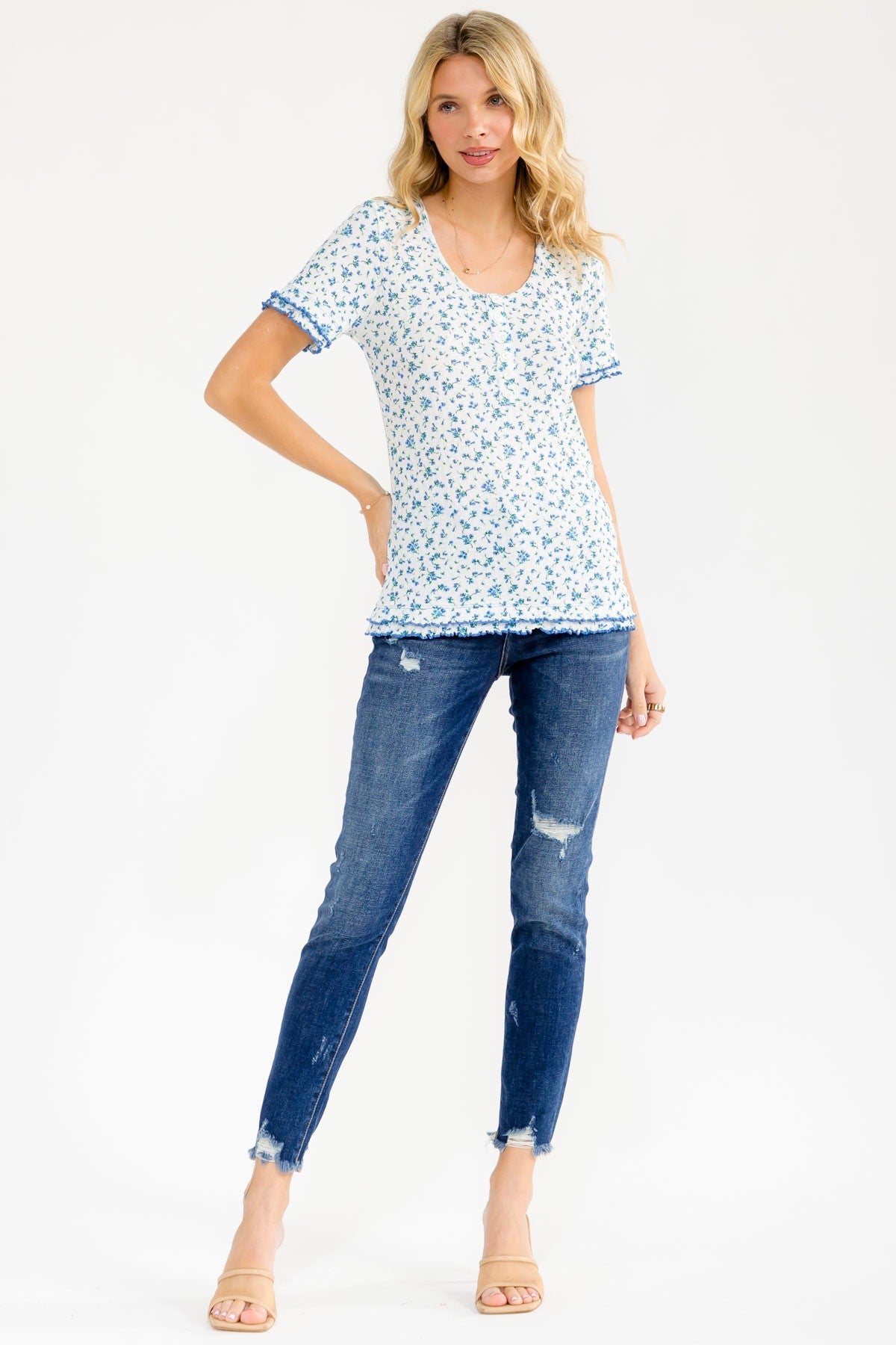 woman wearing a white floral tee with blue accents and short sleeves, paired with distressed skinny jeans