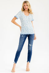 woman wearing a white floral tee with blue accents and short sleeves, paired with distressed skinny jeans