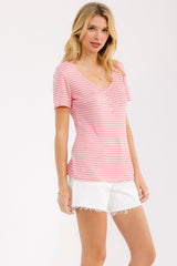 woman wearing a pink and white striped short sleeve top with a v-neckline and buttons, paired with white shorts