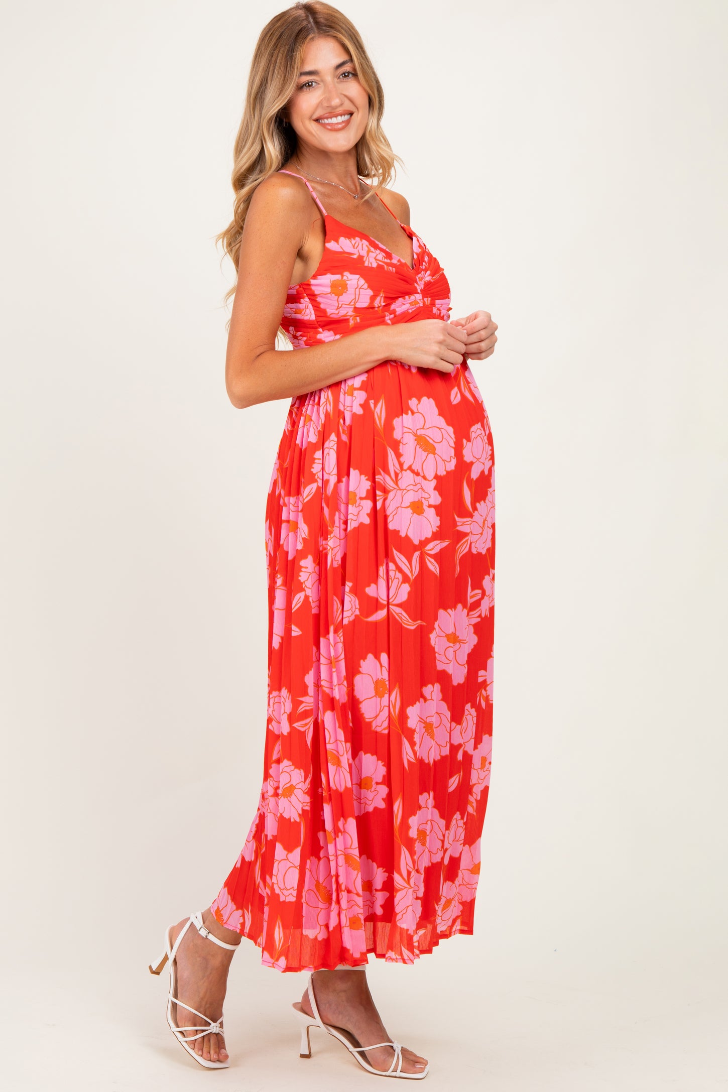 woman wearing a red floral maternity maxi dress with spaghetti straps, showing her baby bump