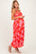 woman wearing a red floral maternity maxi dress with spaghetti straps, showing her baby bump