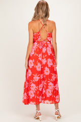 woman wearing a red floral midi maternity dress with a tie back and pleated skirt, showing a baby bump
