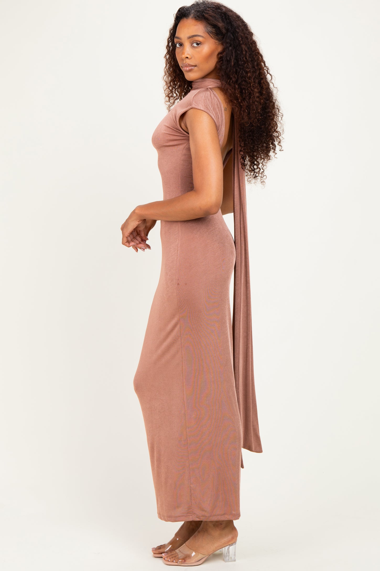 woman wearing a rose pink fitted maxi dress with short sleeves and open back detail, styled with transparent heels