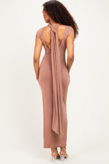 woman wearing a rose gold backless maxi dress with a tie detail at the neck and a fitted silhouette